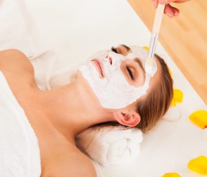 woman lying on her back having chemical peel applied to her face