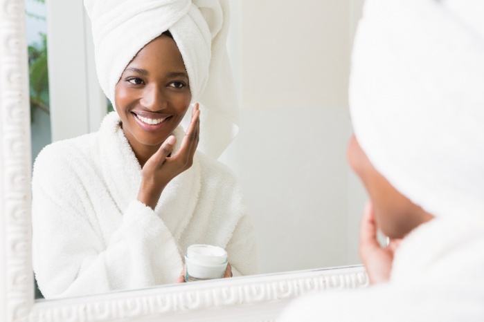 attractive woman fresh from shower applying skin care product