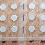 A back covered in a grid pattern of white circles covered in tape where allergens are tested.