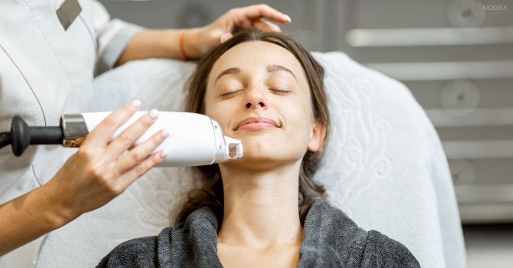 Woman receiving laser skin resurfacing on her face from a provider (MODELS).