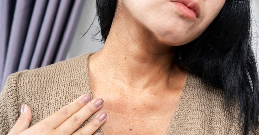 Woman examining her neck and collarbones (MODEL)