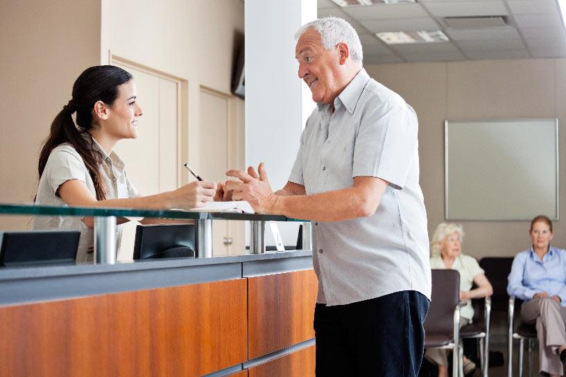 Man speaking to staff member at reception desk