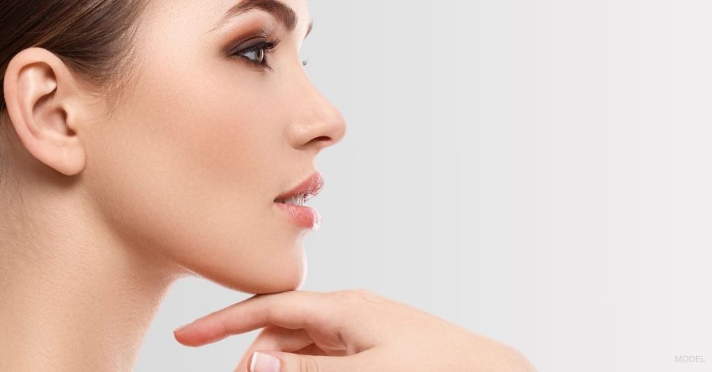 A woman's face side profile with her hand on her chin. (Model)