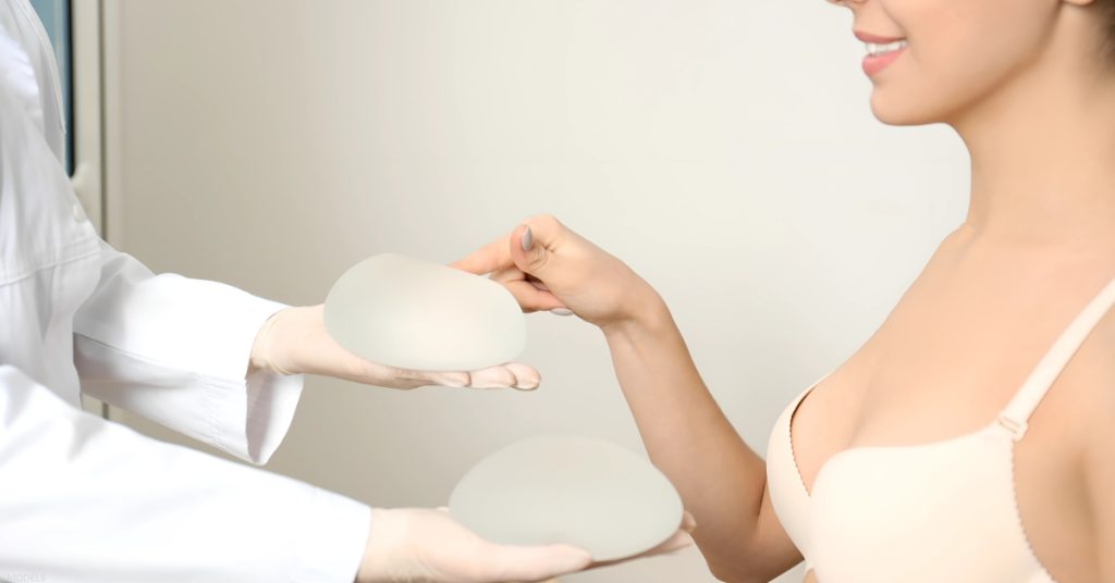 Woman wearing a bra touching breast implants during a doctor consultation (models)