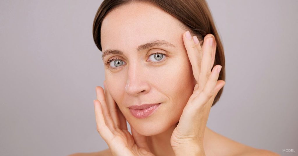 A woman with their hands on their face. (Model)