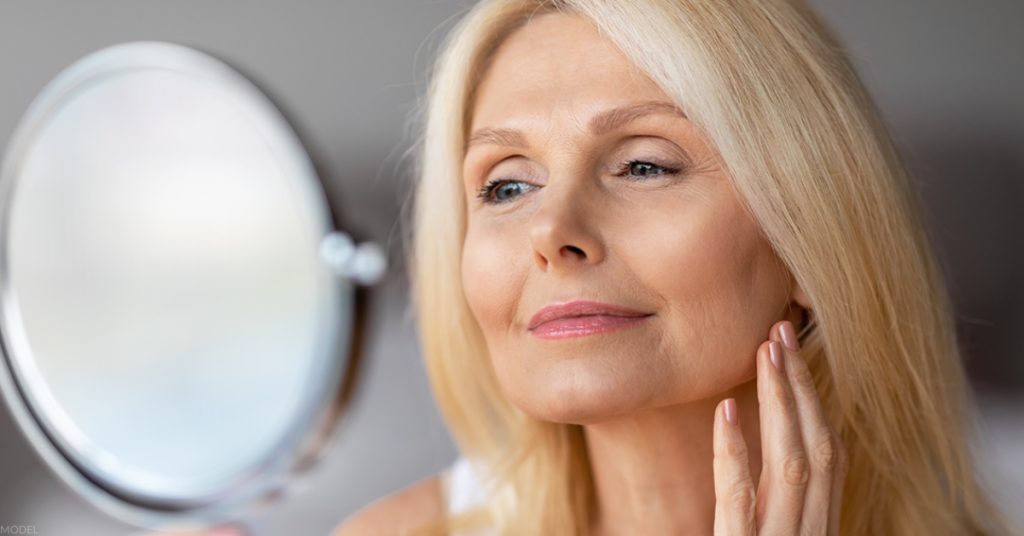 Woman admiring her appearance in the mirror after BOTOX® Cosmetic treatment (Model).
